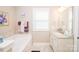 Well-lit bathroom with single vanity, soaking tub, window, and neutral color palette at 9026 Raven Top Dr, Mint Hill, NC 28227