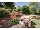 Beautiful landscaping featuring a rock wall, vibrant flowers, and stone steps leading up a gentle hill at 9026 Raven Top Dr, Mint Hill, NC 28227