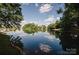 Picturesque pond reflecting the sky and surrounding trees and homes, showcasing a tranquil neighborhood view at 9026 Raven Top Dr, Mint Hill, NC 28227
