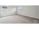 An empty bedroom with neutral carpet, white trim, and bright natural light from two windows at 9956 Manor Vista Trl, Kannapolis, NC 28027
