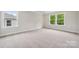 Bright bedroom with neutral carpeting, two windows, and baseboard trim at 9956 Manor Vista Trl, Kannapolis, NC 28027