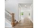 Bright hallway featuring wood-look floors, white trim, a staircase, and an open view into the living room at 9956 Manor Vista Trl, Kannapolis, NC 28027