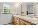 Bathroom with double sinks, wooden cabinets, a window, and a tiled floor at 100 Brookstone Dr, Mount Holly, NC 28120