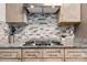 A close up of the kitchen backsplash and stovetop shows granite countertops, modern cabinets, and decorative plant accents at 100 Brookstone Dr, Mount Holly, NC 28120