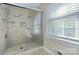 Shower with glass door, neutral tile, and window bringing in natural light, creating a spa-like experience at 10016 Tealridge Ln, Charlotte, NC 28277