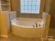 Large garden tub in bathroom with tiled surround and glass block window above at 10817 Bere Island Dr, Charlotte, NC 28278