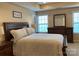 Cozy bedroom features a dark wood bed frame, matching dresser with mirror, and large windows at 10817 Bere Island Dr, Charlotte, NC 28278