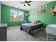 Cozy bedroom featuring bright green walls, a ceiling fan, and two windows at 1305 Kings Grove Dr, York, SC 29745