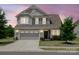 Charming two-story home at dusk with manicured lawn, gray siding, and attached two-car garage at 1305 Kings Grove Dr, York, SC 29745