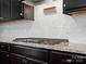 Close up of cooktop featuring granite counters, white backsplash, and dark cabinetry at 1305 Kings Grove Dr, York, SC 29745