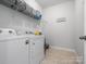 Bright laundry room featuring a side-by-side washer and dryer, plus upper shelving for storage at 1305 Kings Grove Dr, York, SC 29745