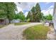 Large backyard with a gravel driveway, storage sheds, wooden fence, and mature trees at 1415 Midlake Rd, Kannapolis, NC 28083