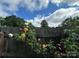 A rose bush climbs a wooden fence beneath a blue sky with fluffy white clouds at 1415 Midlake Rd, Kannapolis, NC 28083