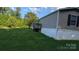 A single-story home with a small deck is surrounded by a beautiful yard and trees at 142 Sandra Dr, Statesville, NC 28625