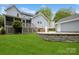 Wide view of backyard featuring a blue house, detached garage, retaining wall, screened porch, and lush lawn at 16612 Grapperhall Dr, Huntersville, NC 28078
