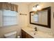 Bathroom with a single sink vanity, large mirror, and window at 16612 Grapperhall Dr, Huntersville, NC 28078