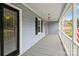 Inviting covered front porch with black door, grey siding, and wood decking at 16612 Grapperhall Dr, Huntersville, NC 28078