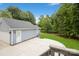 View of detached garage featuring blue siding, white doors, well-manicured lawn, and an aggregate patio at 16612 Grapperhall Dr, Huntersville, NC 28078