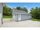 View of the detached garage featuring blue siding, white doors, large driveway, and manicured front lawn at 16612 Grapperhall Dr, Huntersville, NC 28078