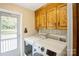 Bright laundry room featuring a washer, dryer, wooden cabinets, shelving, and access door to the outside at 16612 Grapperhall Dr, Huntersville, NC 28078