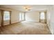 Bright living room features neutral carpet, ceiling fan, and exterior double doors at 16612 Grapperhall Dr, Huntersville, NC 28078