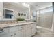 Bright bathroom featuring a double vanity with granite counters, a large mirror and walk-in shower at 16831 Alydar Commons Ln, Charlotte, NC 28278