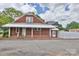 Rear exterior view featuring a brick facade, covered porch, and a fenced yard with paved area at 2036 1St Sw Ave, Hickory, NC 28602