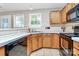 A compact kitchen features tile countertops and backsplash, stainless steel sink, and wood cabinets at 2045 Flushing Ct, Charlotte, NC 28215