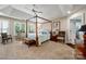Bright bedroom with a four-poster bed, tray ceiling, and plantation shutters on the windows at 21216 Norman Shores Dr, Cornelius, NC 28031