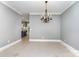 Bright dining room with a decorative chandelier, neutral walls, and tile flooring, with a glimpse into the kitchen at 239 N Faulkner Way, Davidson, NC 28036