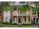 Charming two-story brick home with a welcoming front porch and balcony, surrounded by lush landscaping and mature trees at 239 N Faulkner Way, Davidson, NC 28036