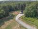 Aerial view of a property featuring a long driveway to a home, surrounded by lush trees at 2676 Will Schronce Rd, Iron Station, NC 28080