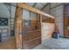 Inside view of a wooden barn stall with a metal gate and a window at 2676 Will Schronce Rd, Iron Station, NC 28080