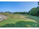 Expansive, grassy property with wooden split-rail fencing and a distant barn at 2676 Will Schronce Rd, Iron Station, NC 28080