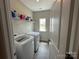 The laundry room with tile floors features new washer and dryer, shelves, and natural light at 348 Ox Bow Cir, Mount Holly, NC 28120