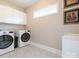 Well-lit laundry room featuring modern appliances, white cabinets, and decorative tile flooring at 7040 Edenderry Dr, Charlotte, NC 28270