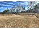 Large, flat, fenced backyard with dormant grass and mature trees behind it at 809 Brown Creek Dr, Matthews, NC 28104