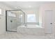Luxurious bathroom features a frameless glass shower, a separate tub, and marble tile throughout at 809 Brown Creek Dr, Matthews, NC 28104