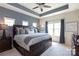 Main bedroom featuring tray ceilings, a ceiling fan, and multiple windows for natural light at 9521 Ainslie Downs St, Charlotte, NC 28273