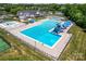 Aerial view of the community pool with waterslides, recreational pool, tennis courts, and lots of lounge chairs at 9639 Ravenscroft Nw Ln, Concord, NC 28027