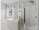 Bathroom featuring a glass enclosed shower, soaker tub, window, and white marble flooring at 9639 Ravenscroft Nw Ln, Concord, NC 28027