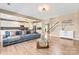 Open-concept living area with wood-look flooring, a modern couch, natural light, and views of the staircase and kitchen at 9639 Ravenscroft Nw Ln, Concord, NC 28027