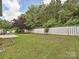 Large, fenced back yard with green grass and mature trees at 9700 Ravenscroft Nw Ln, Concord, NC 28027