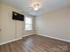 This bedroom has hardwood floors, a ceiling fan, a window and mounted TV at 9700 Ravenscroft Nw Ln, Concord, NC 28027