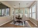 Sunlit dining area with modern lighting and a view of the lush greenery outside the windows at 9700 Ravenscroft Nw Ln, Concord, NC 28027