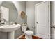 Modern powder room featuring a pedestal sink, round mirror, and gray walls at 1044 Shiloh Bend Trl, Fort Mill, SC 29715