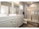 Well-lit bathroom with double vanity, framed mirror, a tiled walk-in shower, and wood-look flooring at 105 Chase View Ln, Troutman, NC 28166