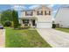 Charming two-story home featuring tan siding, a well-manicured lawn, and an attached two-car garage at 1105 Bottle Brush Ln, Harrisburg, NC 28075