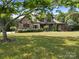 View of a beautiful stone-clad home with a well-manicured lawn and mature trees at 14010 Mccord Rd, Huntersville, NC 28078