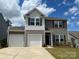 Attractive two-story home featuring a two-car garage, dark shutters, and landscaped front yard on a sunny day at 165 Clove Hitch Dr # I281, Statesville, NC 28677